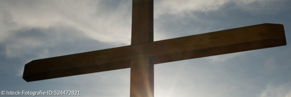 Kreuz vor sonnigem Himmel