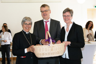 Regionalbischöfin Dr. Greiner und Dekanin Ott-Frühwald übergeben Pfarrer Harder einen handgemachten Korb