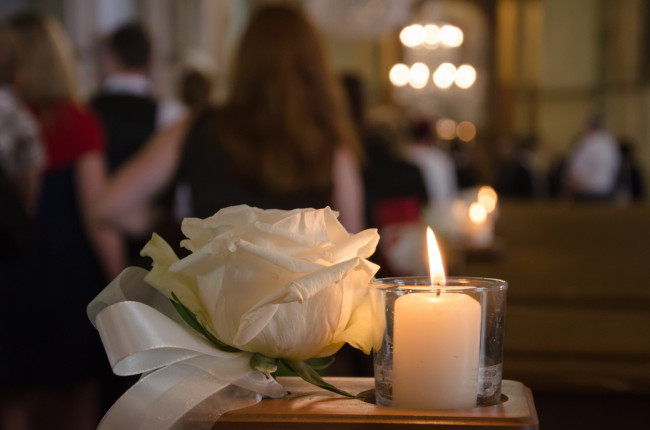 Kerze und weiße Rose in Kirche 